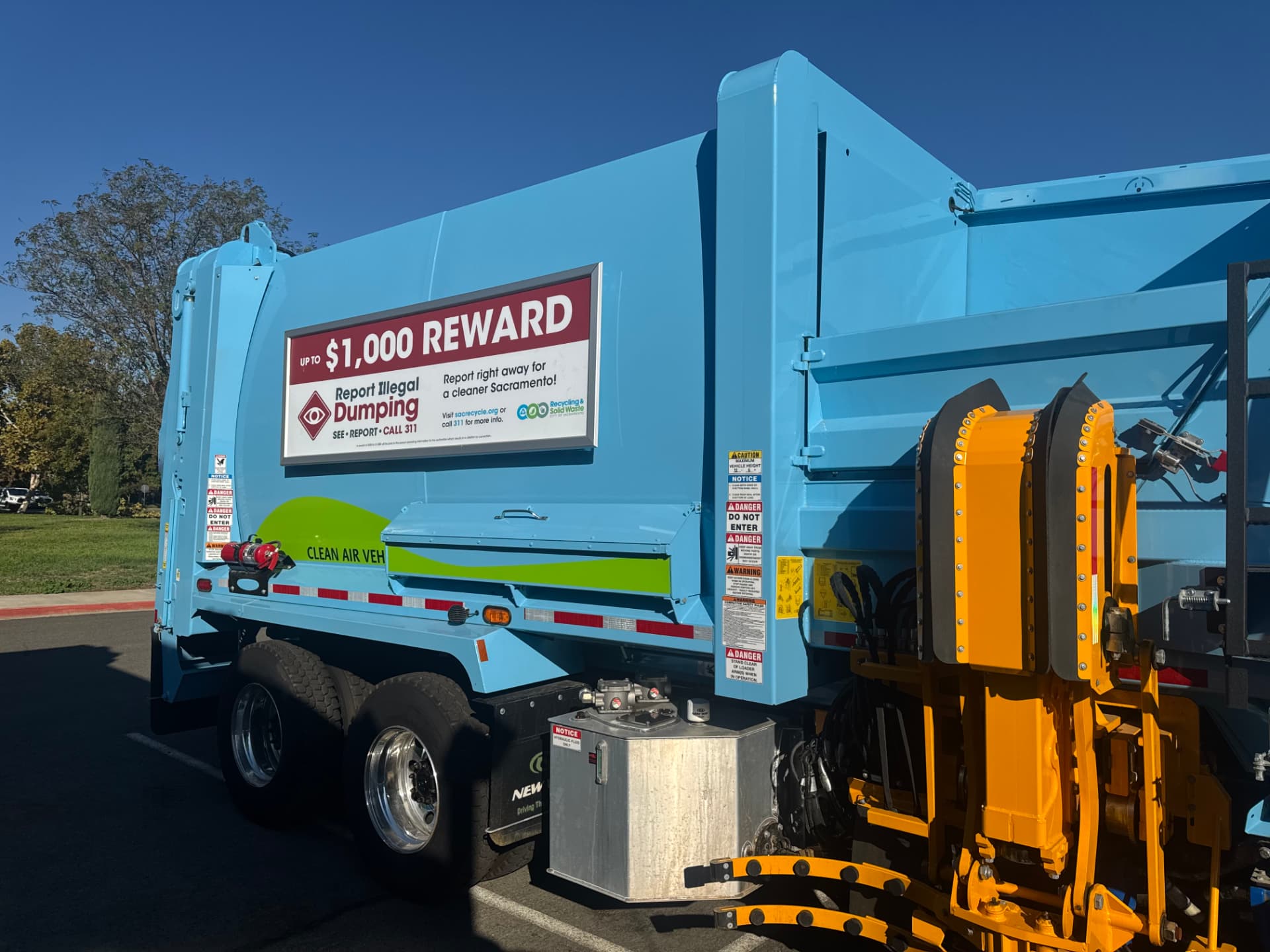 City of Sacramento collection vehicle with a Roadway panel offering a reward for reporting illegal dumping